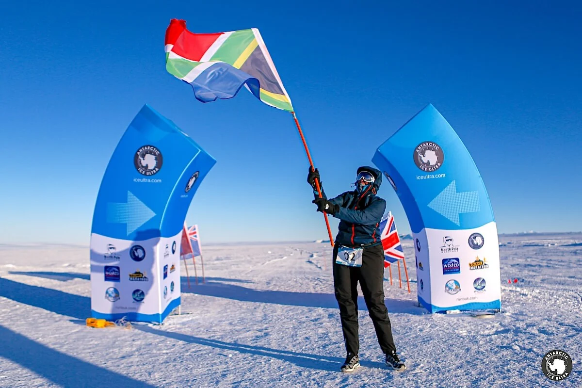 Antarctic Ice Ultra finisher holding a flag